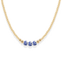 Gold necklace with three blue porcelain ceramic beads on a white background