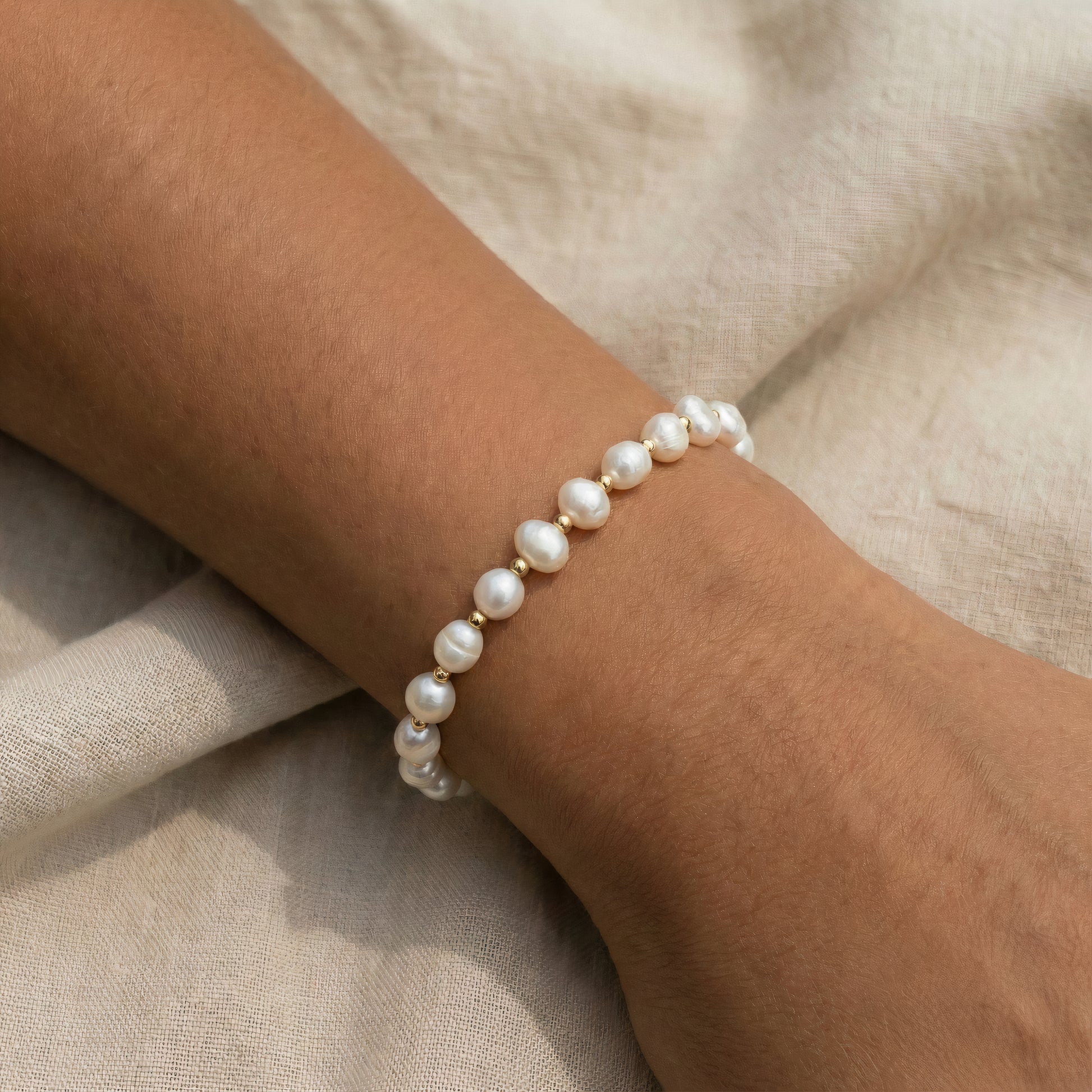 Pearl beaded bracelet on a wrist with a neutral background