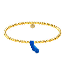 Gold beaded bracelet with a blue accent on a white background