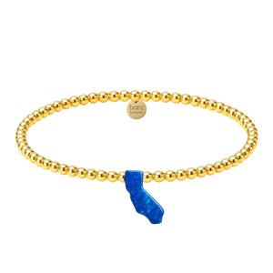 Gold beaded bracelet with a blue accent on a white background