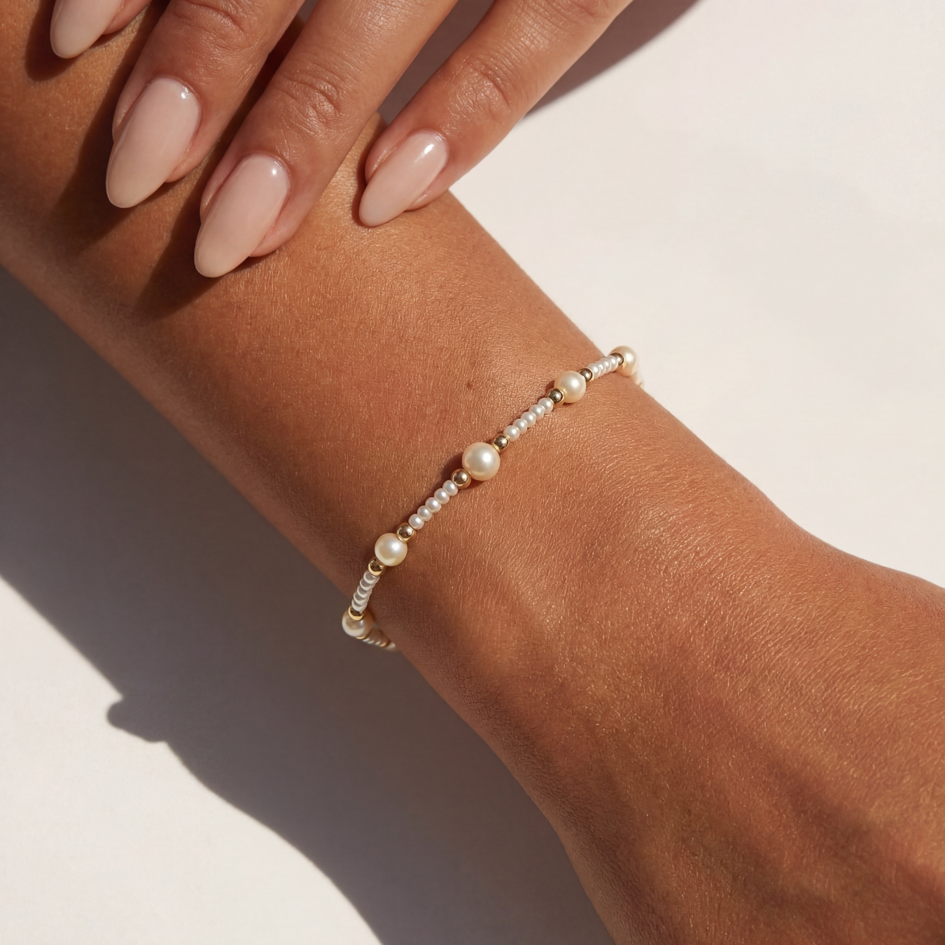 Pearl beaded bracelet on a wrist with a neutral background