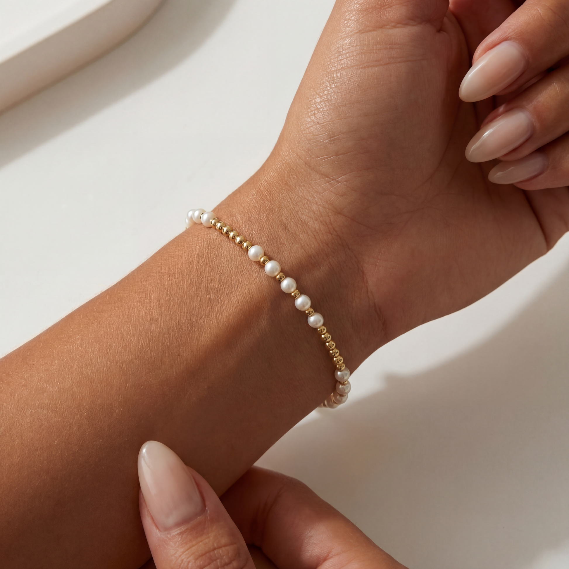 Pearl beaded bracelet on a wrist with a neutral background