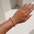 Hand wearing a pearl beaded bracelet on a neutral background