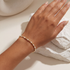 Hand wearing a beaded pearl bracelet against a neutral background