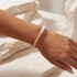 Gold and pearl beaded bracelet on a wrist with a neutral background