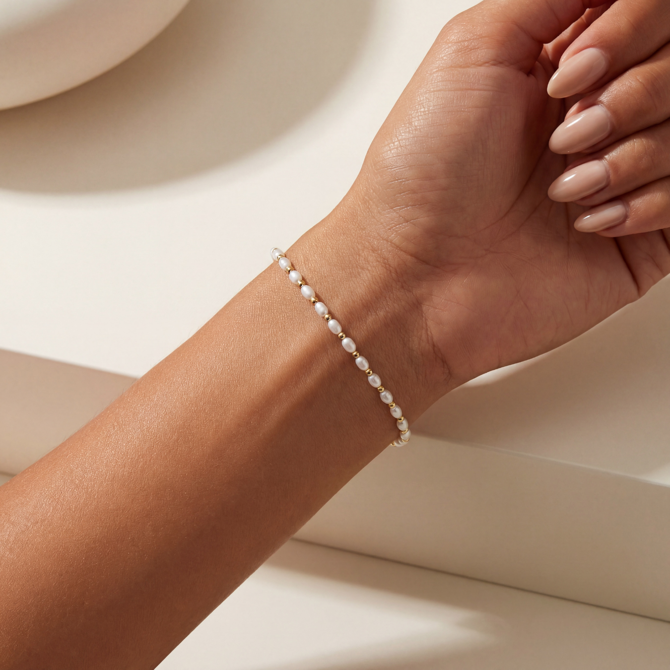 Pearl beaded bracelet on a wrist with a neutral background