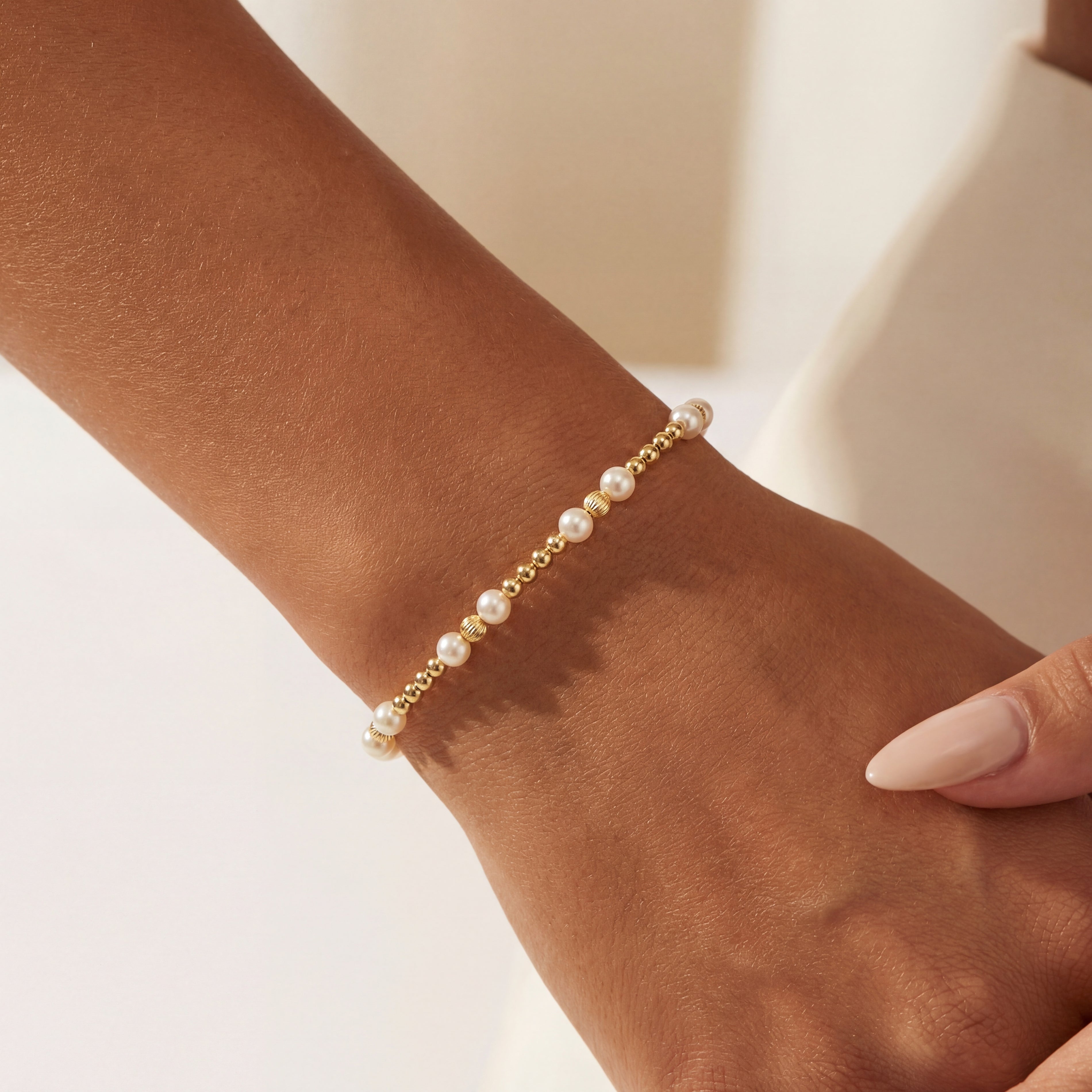 Pearl beaded bracelet on a wrist with a neutral background