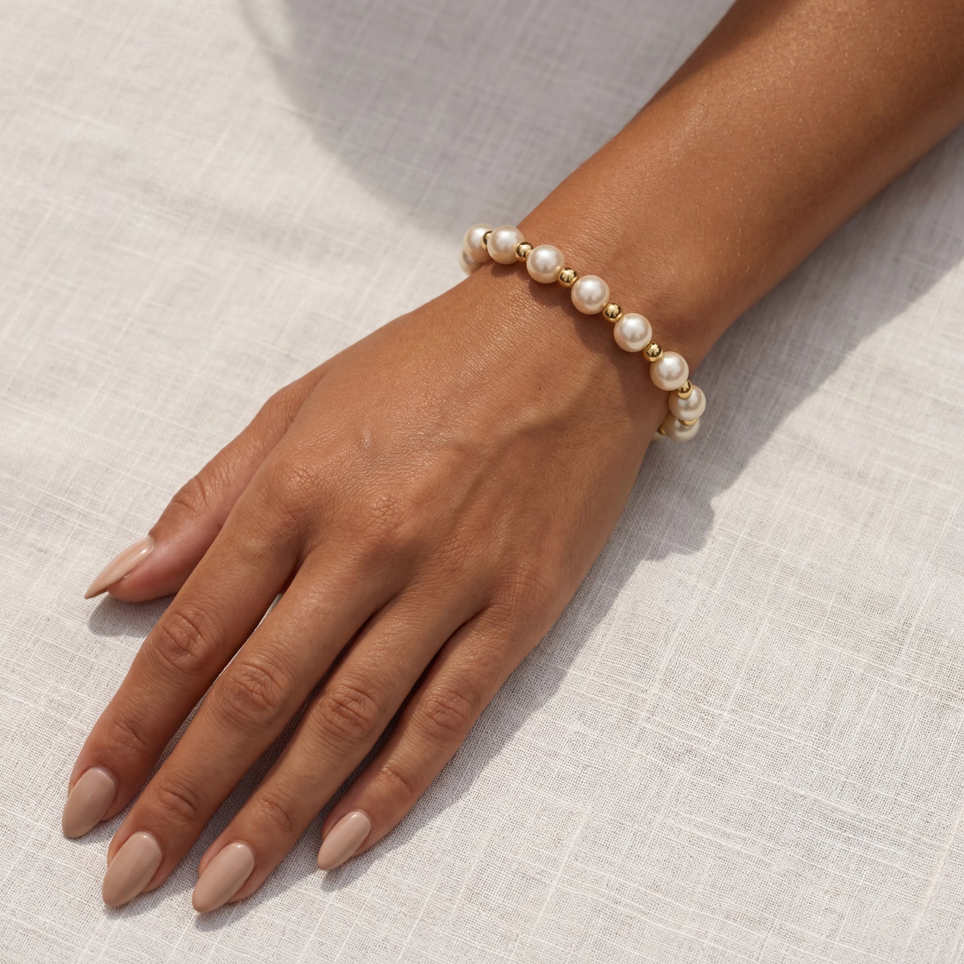 Pearl beaded bracelet on a wrist against a neutral background