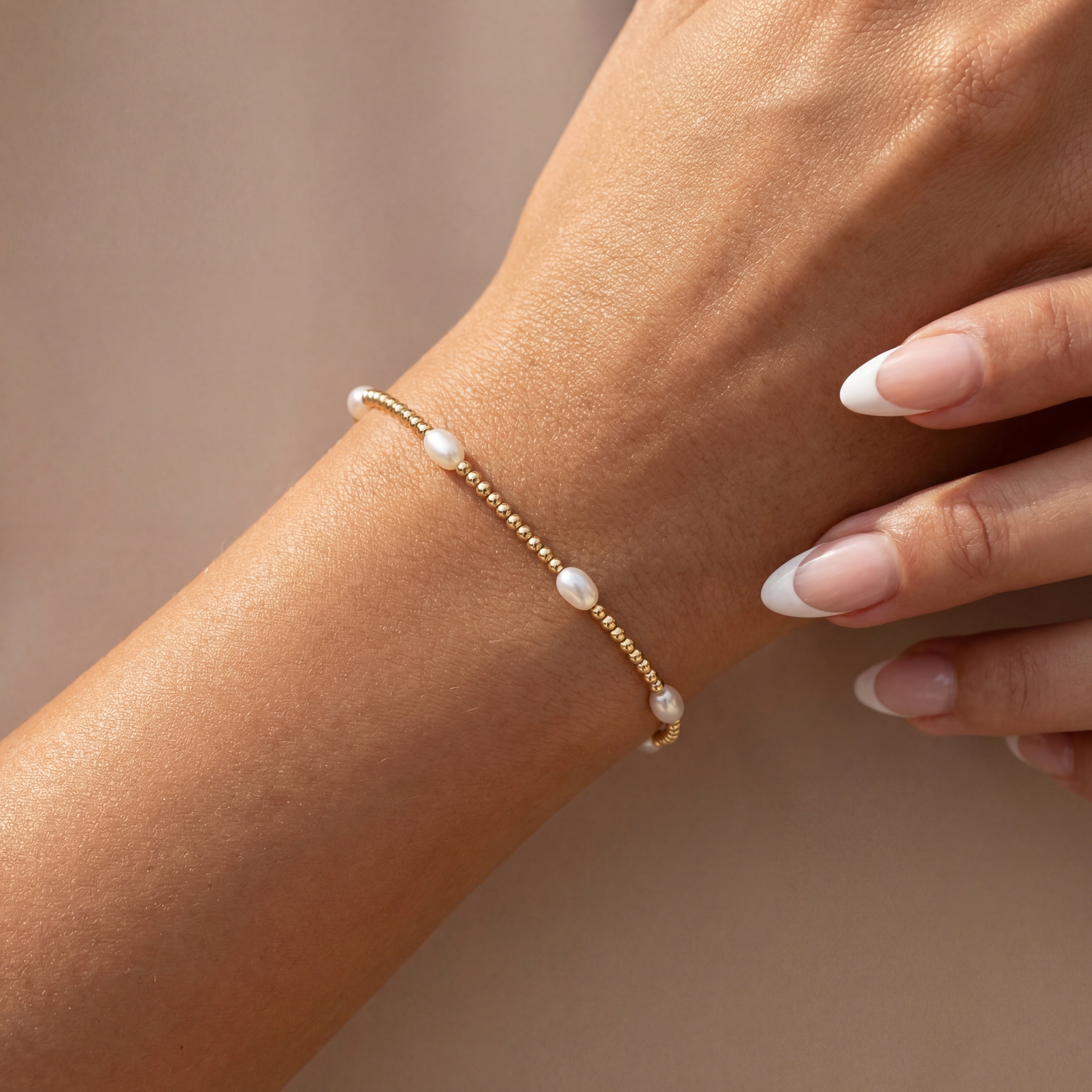 Pearl beaded bracelet on a wrist with a neutral background