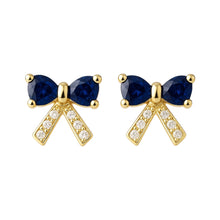 Gold bow-shaped earrings with blue gemstones on a white background